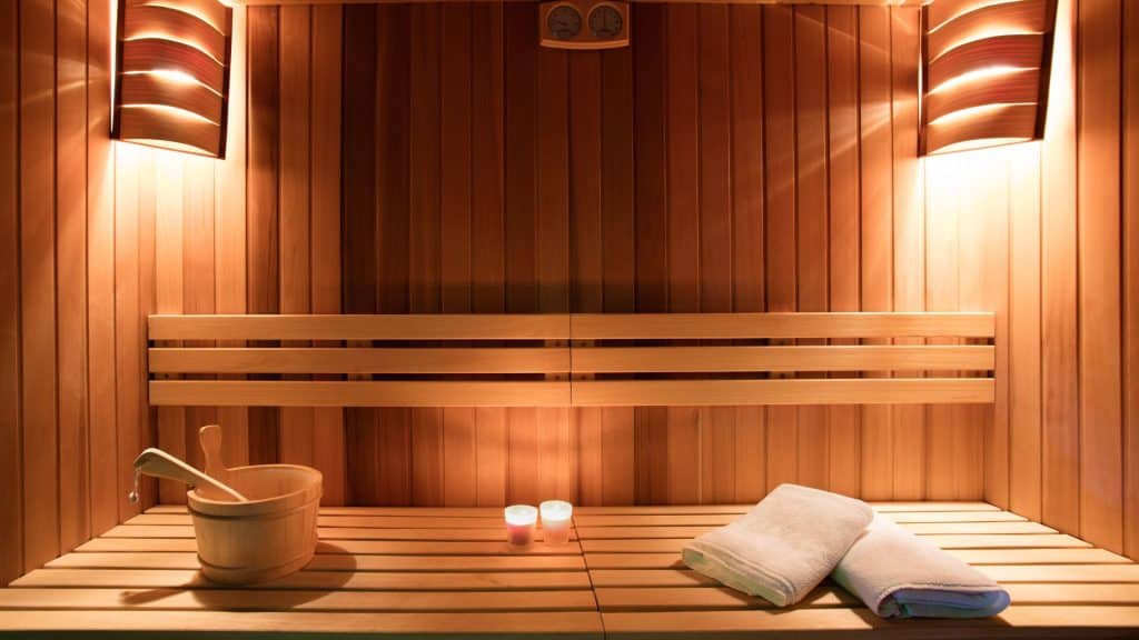 Interior of a wooden sauna with folded towels, candles, and a wooden water bucket, highlighting alcohol detox myths.
