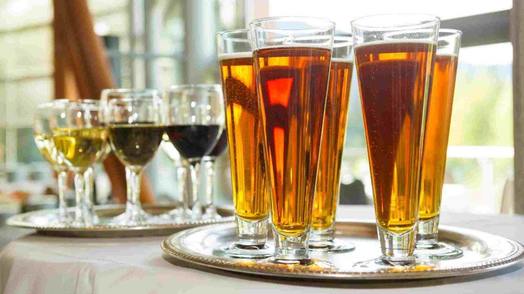 Assorted glasses of beer and wine on silver trays illustrating different alcohol types.