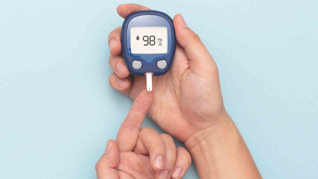 Person using a glucose meter to check blood sugar, symbolizing how alcohol impacts ketosis, insulin, and fat burning on keto.
