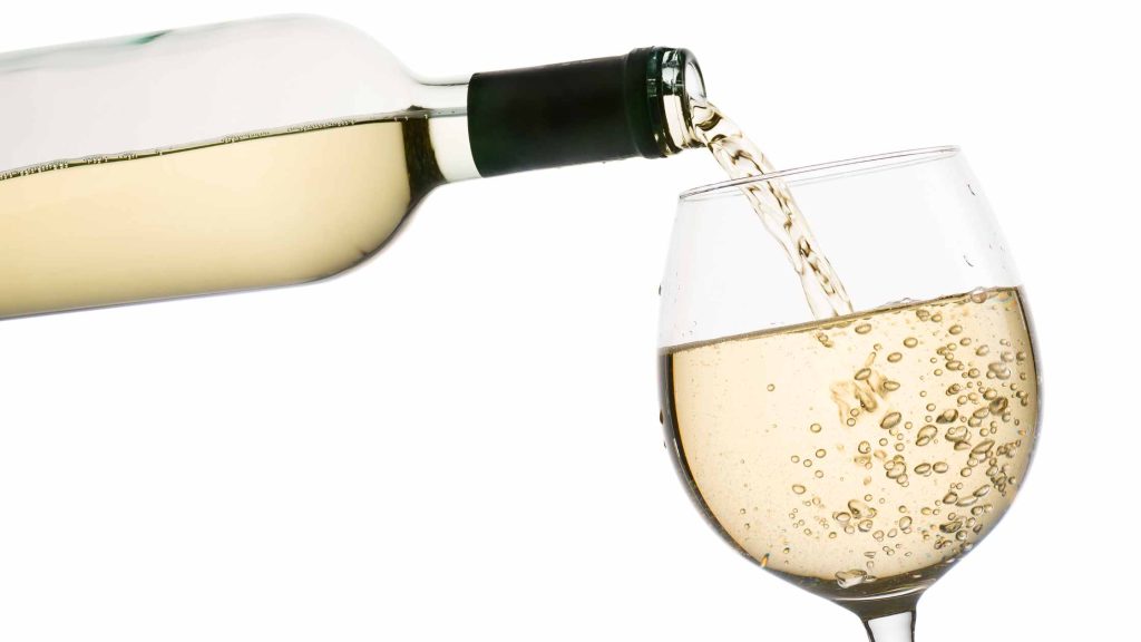 White wine being poured into a glass, highlighting it as a better choice than red wine to reduce facial flushing.