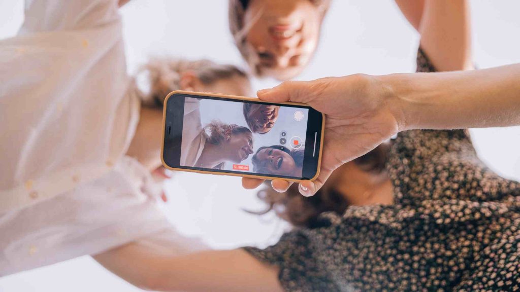 Friends smiling while recording a video together, showing positive social media use for connection and mental health.