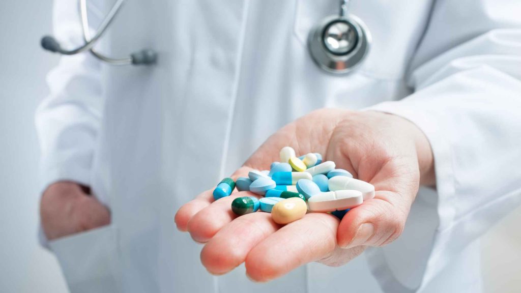 Doctor holding assorted pills in palm, representing medical insight into Suboxone’s half-life and dosage effects.