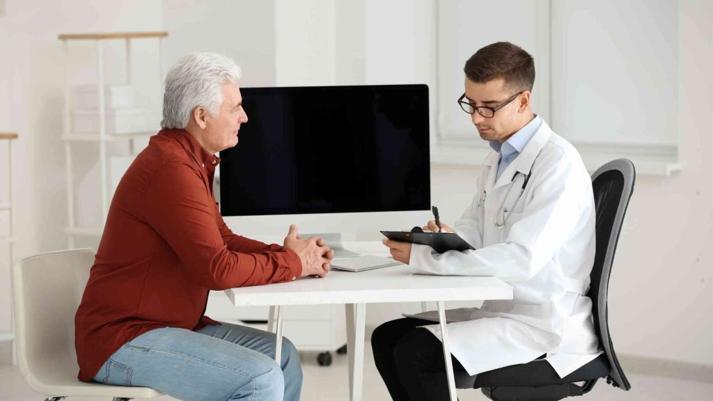Older man consulting with a doctor in an office, highlighting the importance of seeking medical help when needed.