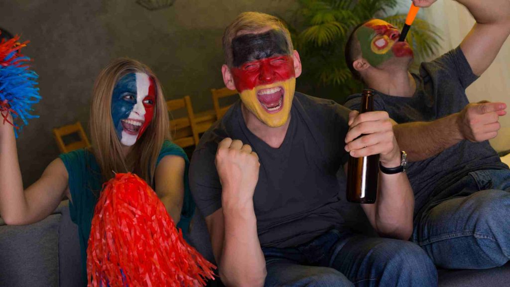 Group of friends with face paint cheering and drinking, symbolizing risky behavior like combining medications for euphoria.