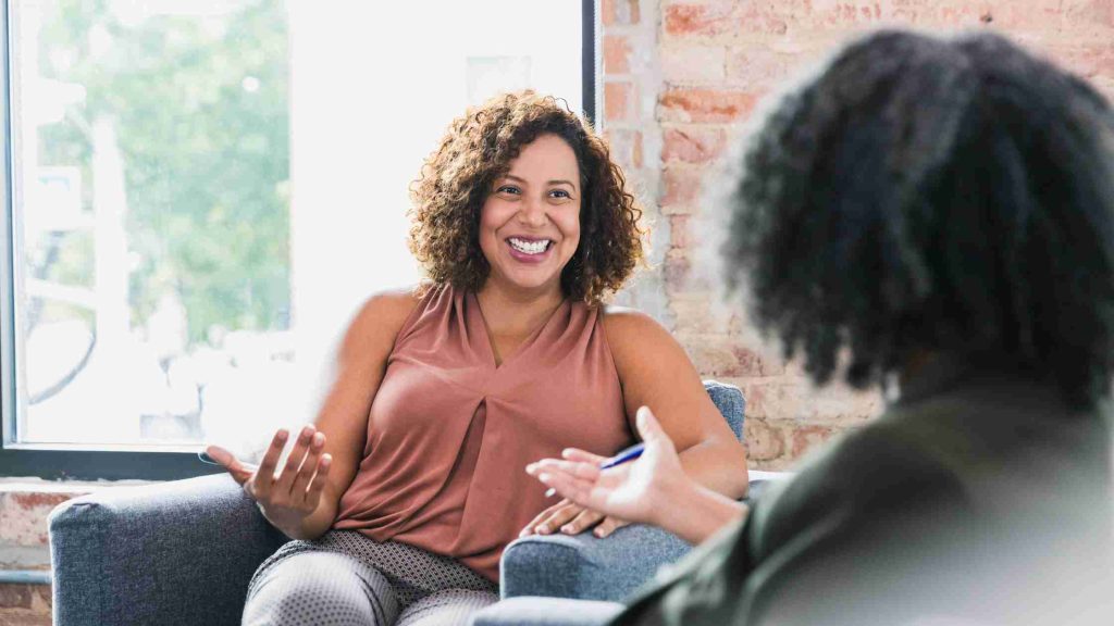 Smiling woman in a therapy session, symbolizing Blue Cross-covered alcohol rehab programs like standard outpatient therapy.