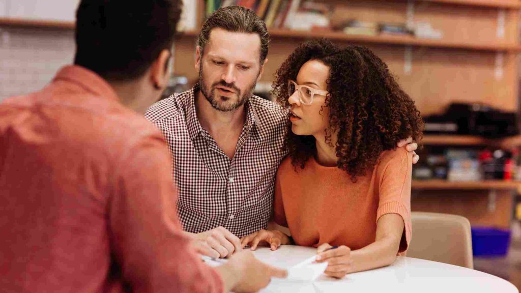 Couple consulting with advisor at a table, reviewing documents to verify Cigna PPO inpatient coverage details.