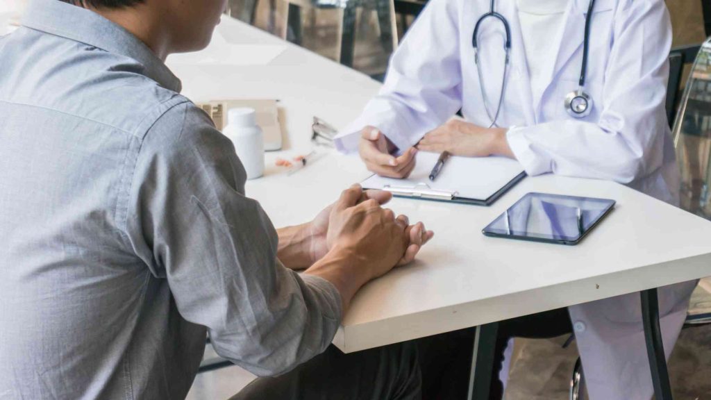 Doctor providing medical supervision to a patient in a clinical setting, illustrating inpatient addiction treatment care.
