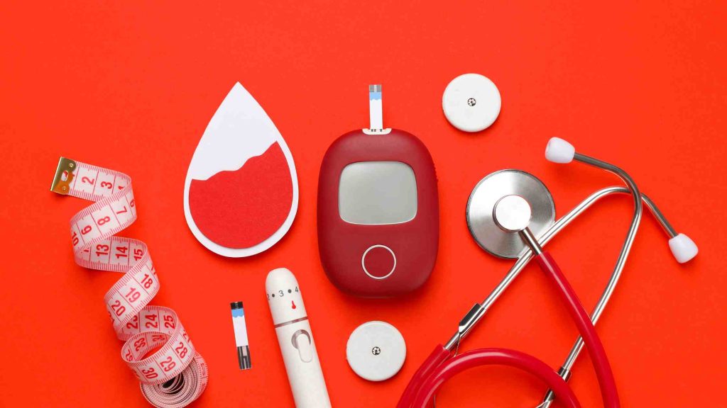 Medical tools and blood sugar monitor arranged on red background, symbolizing Aetna PPO’s aftercare and medication coverage.