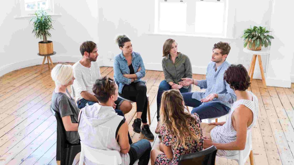 Group therapy session with people sharing experiences, illustrating that Aetna does provide coverage for outpatient rehab.